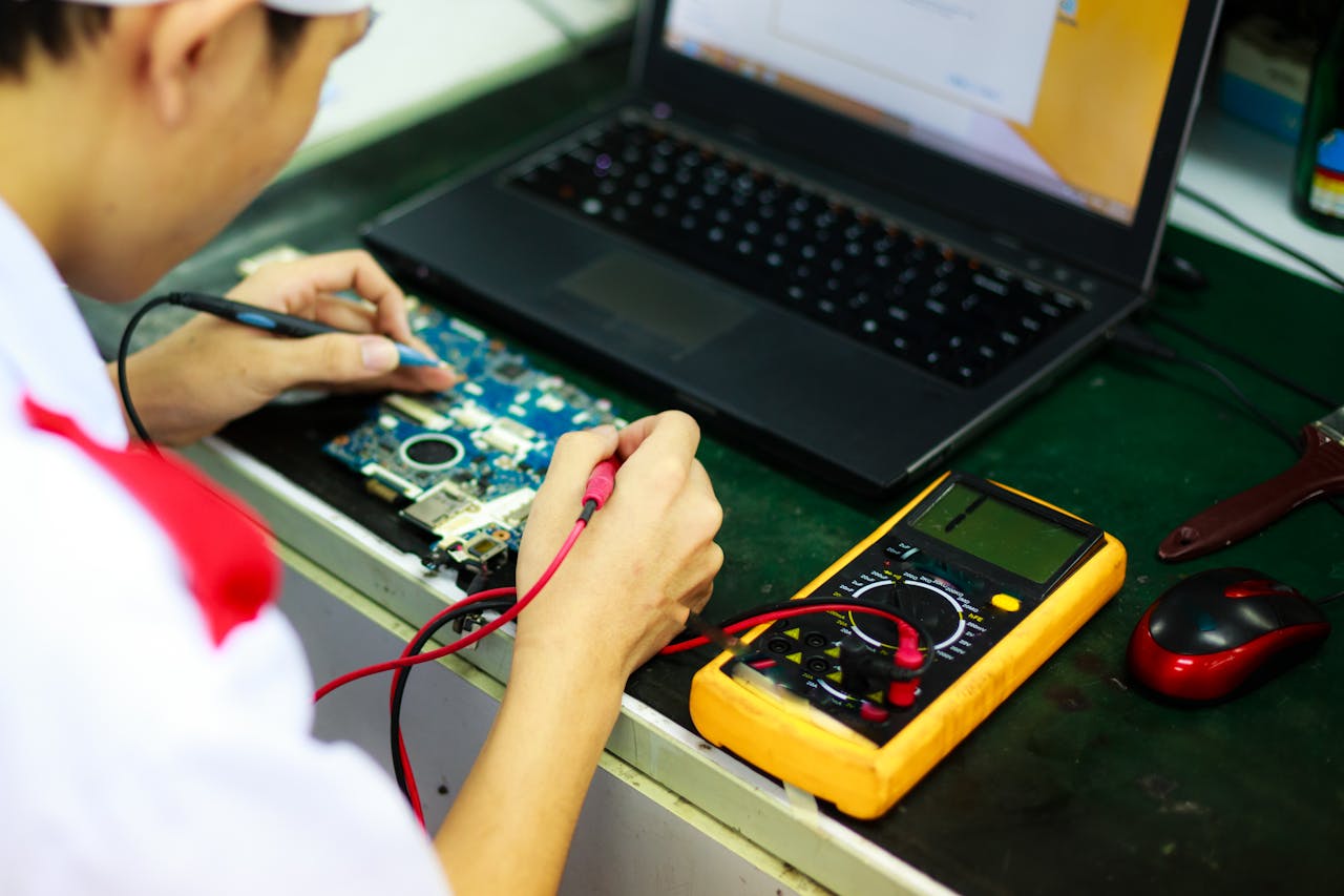 services-04 Technician working on a laptop with multimeter in a professional workspace.
