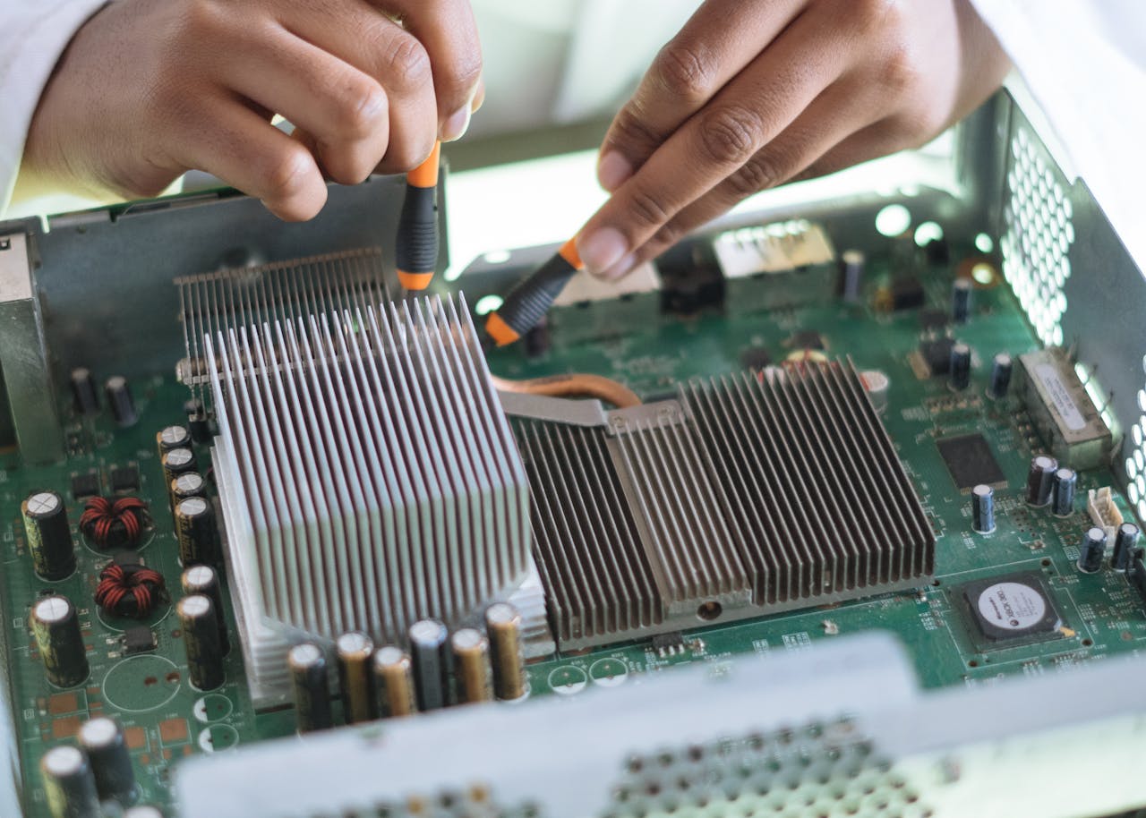 team-02 Close-up of a technician repairing a computer motherboard, focusing on microprocessor and heat sink.