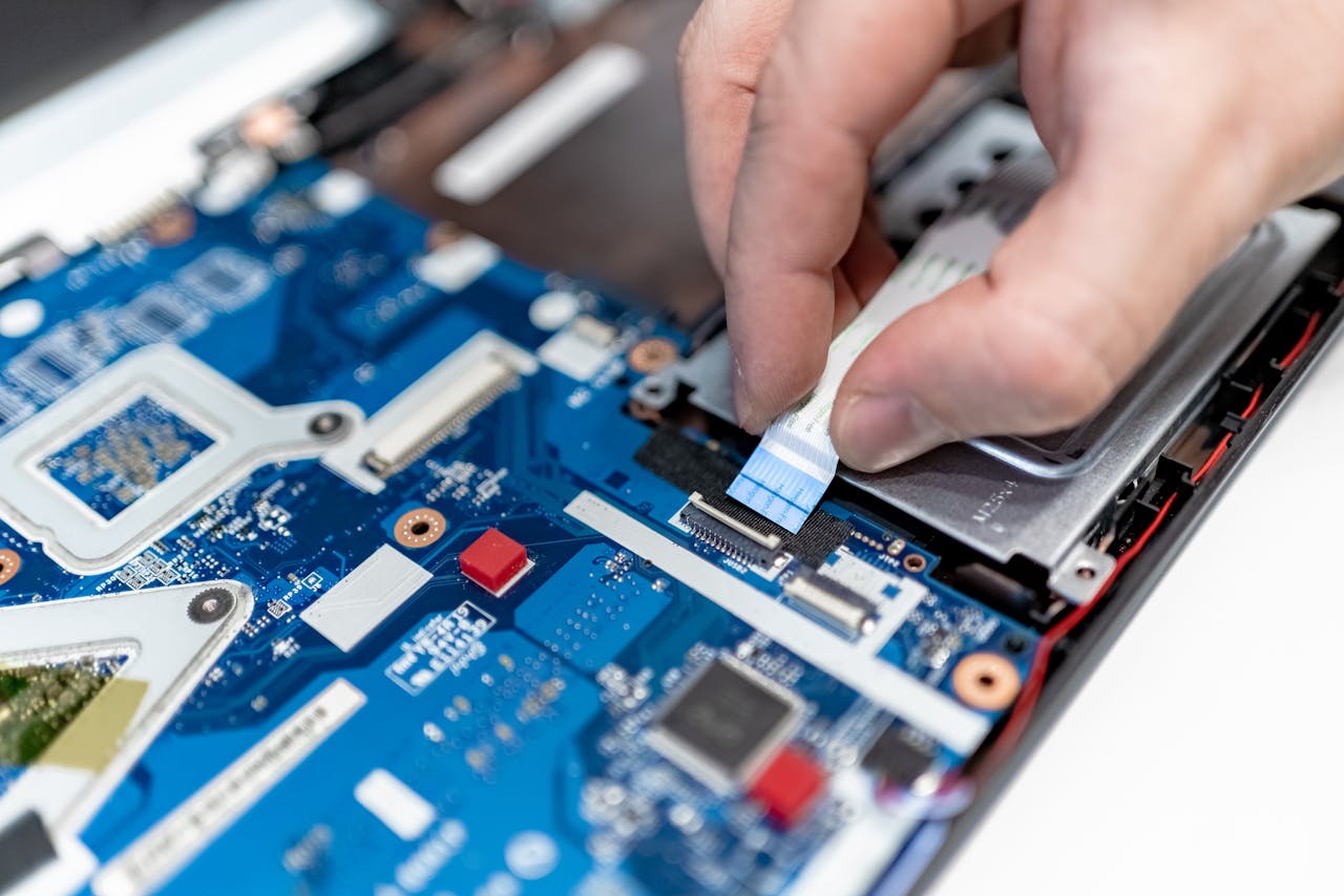 who-we-are Close-up image of hands repairing a laptop circuit board showing intricate details of electronics.